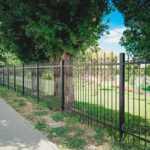 A black metal fence along the sidewalk on a city street.